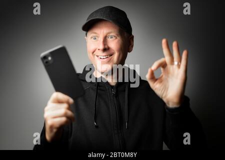Man in black clothes happy with the message on the phone or the phone itself. Stock Photo
