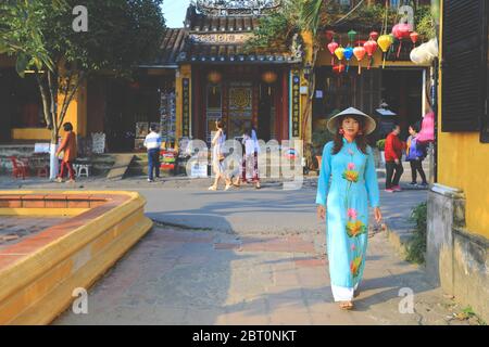Hoi An, Vietnam - February 7, 2018 : Woman in Ao Dai dress walking on the street in Hoi an, Vietnam Stock Photo