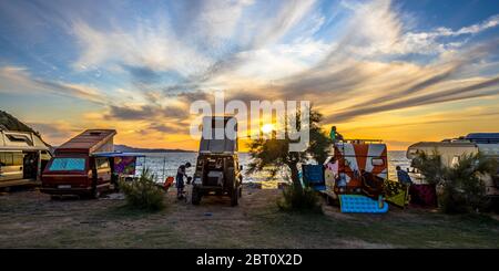 Campers and Motorhomes overlooking sunset in the Mediterranean sea from their campsite on the beach, Corsica, France Stock Photo