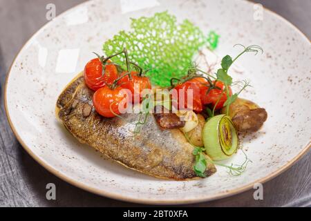 Fried walleye fillet with potatoes, leek, cherry tomatoes and mushrooms on plate Stock Photo