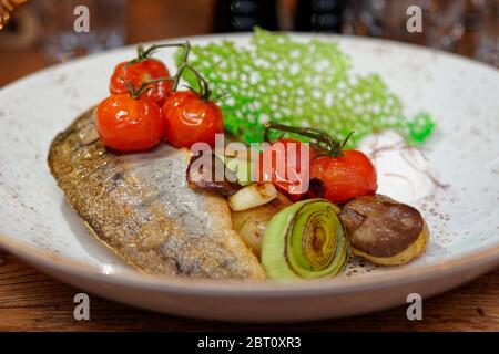 Fried walleye fillet with potatoes, leek, cherry tomatoes and mushrooms on plate Stock Photo