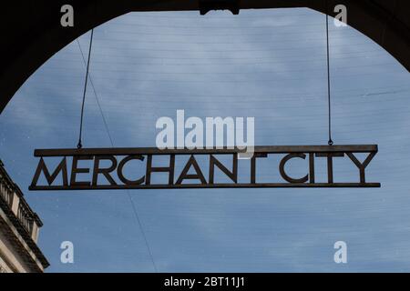 The metal Merchant City sign hanging from an arch at the entrance to Royal Exchange Square in Glasgow, Scotland with a blue sky background Stock Photo