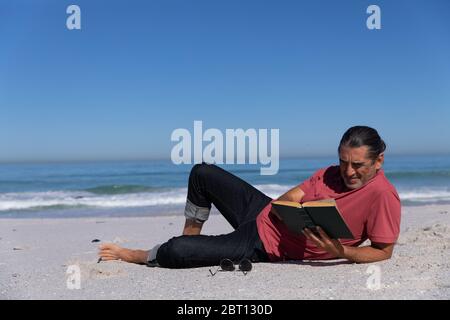 Senior Caucasian man reading a book at the beach. Stock Photo
