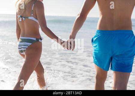 Caucasian couple standing in water at the beach. Stock Photo