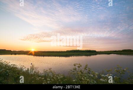 Sheet of altocumulus clouds is beautifully illuminated by the setting sun Stock Photo
