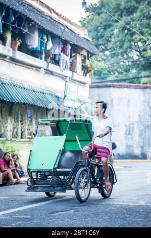 A traditional pedicab or rickshaw makes it way through the streets of the old walled city of Intramuros Manila, The Philippines. Stock Photo