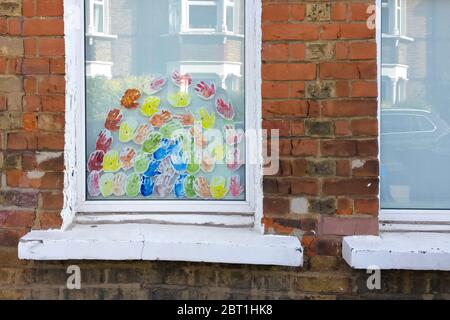 London, United Kingdom - May 04, 2020: Rainbow made of colourful hand prints displayed on local window of house in Lewisham, as sign of appreciation t Stock Photo