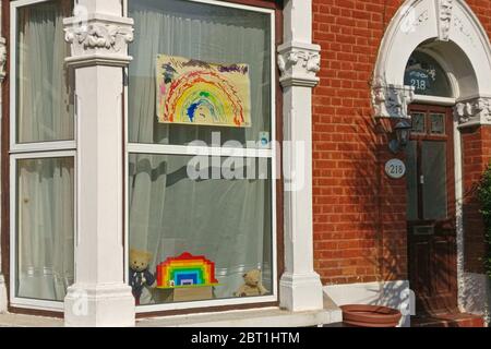 London, United Kingdom - May 04, 2020: Colourful rainbow painted by kids on paper, and another one below made of toy bricks displayed in window of hou Stock Photo