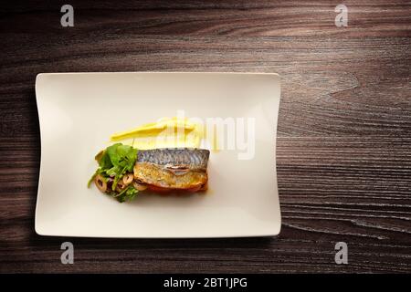 Directly above shot of a stylish Nouvelle Cuisine plate of fish on salad on wooden background Stock Photo