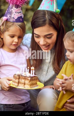 Smiling mother and her child's celebrate children birthday party and blowing candle cake. Stock Photo