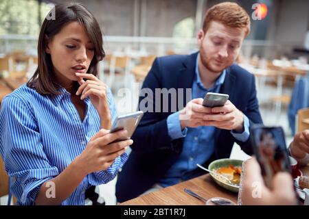 people at lunch in their worlds, distracted from each other by cell phones. not present, social issues, victims of modern technology Stock Photo