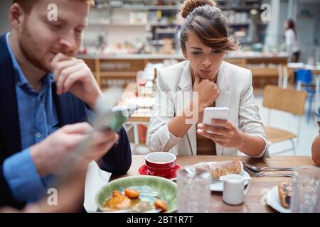 business people  at lunch, not talking, worried, after covid, distracted from each other by cell phones. not present, social issues, recessions, probl Stock Photo