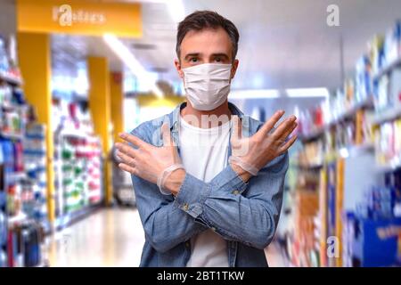 Man showing personal protection of gloves and mask in the aisle of a store with shelves full of products Stock Photo