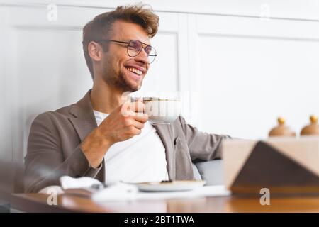 Cheerful young man drinking coffee in cafe Stock Photo