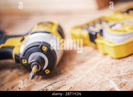 Close Up Of Cordless Black And Yellow Power Drill And Plastic Yellow Box With Set Of Drill Bits. Stock Photo