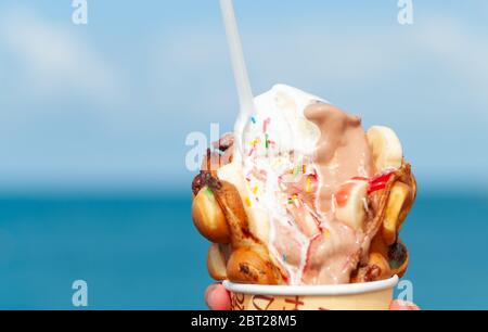 Big ice-cream in Bubble Waffle on a beach. Closeup Stock Photo