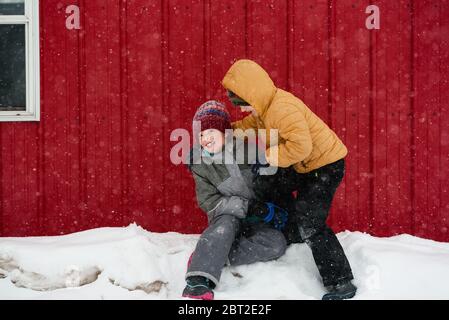 Two children playing in the snow outside a house, USA Stock Photo