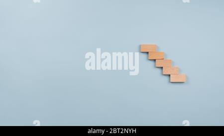 Staircase made of five wooden pegs in a conceptual image. Over blue background with copy space. Stock Photo