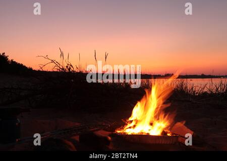 Beach Campfire on Lake. Red sky Superior at sunset as vacation concept Stock Photo