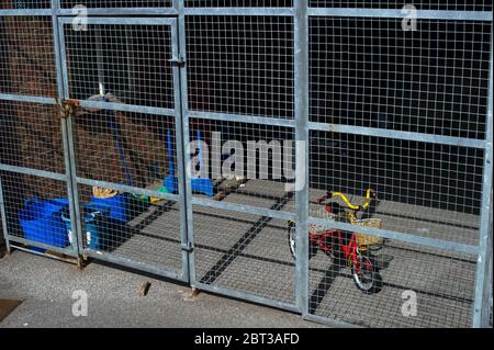 Childs tricycle locked away in compound Stock Photo