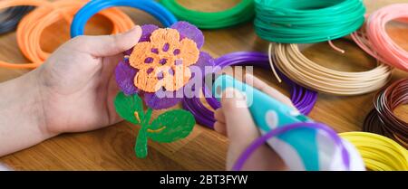 Child using 3D pen. Children hands making flower from colored ABS plastic. Creative hobby at home, technology, leisure, education concept. Selective f Stock Photo