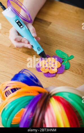Child using 3D pen. Children hands making flower from colored ABS plastic. Creative hobby at home, technology, leisure, education concept. Selective f Stock Photo