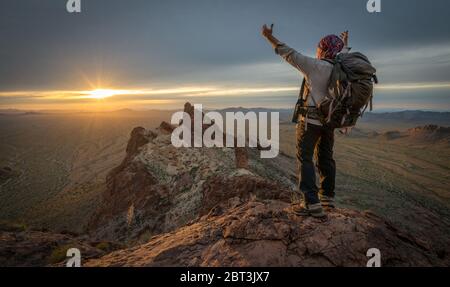 Hiker standing on Kofa Queen Canyon with arms outstretched, Kofa National Wildlife Refuge, Arizona, USA Stock Photo