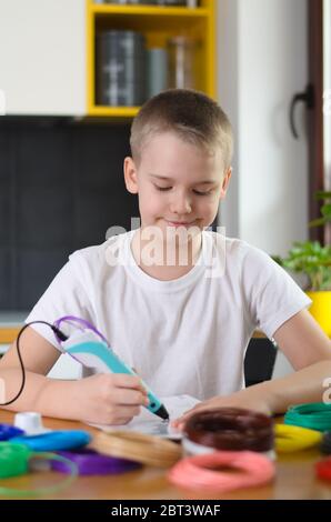 Child using 3D pen. Boy draws on stencil by colored ABS plastic at home. Creative hobby at home, technology, leisure, education concept. Selective foc Stock Photo