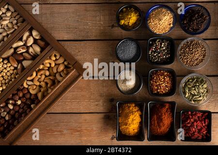 Spices in bowls and nuts in wooden box on a wooden table Stock Photo