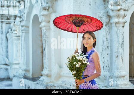 Portrait of a beautiful woman holding flowers at Shwe Nan Daw Monastery, Mandalay, Myanmar Stock Photo