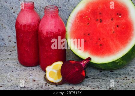 Glass bottles filled with colorful fresh homemade beet and watermelon smoothies Stock Photo