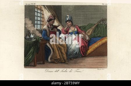 Costume of the women of the island of Tino, Italy, 18th century. One woman reads a book while another lounges on a sofa with a cat and lute. Handcoloured copperplate engraving by Sasso from Giulio Ferrario's Costumes Ancient and Modern of the Peoples of the World, Florence, 1847. Stock Photo