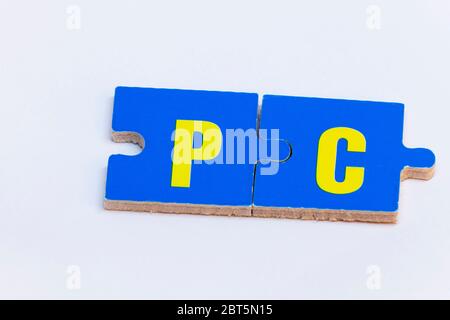 puzzle pieces in blue and yellow forming the word PC on white background Stock Photo