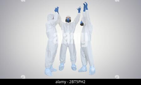 Doctors in hazamat suits stacking hands Team work on gradient background. Stock Photo