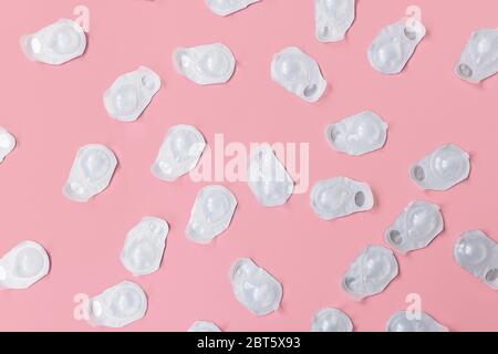 A lot of blisters with contact lenses interspersed on a pink background. Blisters are new and not open.  Stock Photo