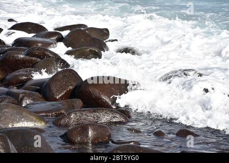 Waves break on stony rocky beach seashore Stock Photo