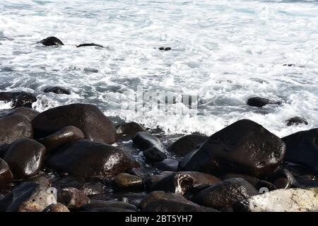 Waves break on stony rocky beach seashore Stock Photo