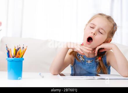 Little girl yawning when making her homework with digital tablet Stock Photo