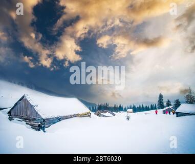 Panoramic view of wooden chalets in Carpathian mountains surrounded with forest at sunset Stock Photo