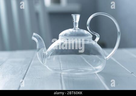 Empty transparent teapot on wooden kitchen table Stock Photo