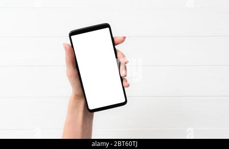 Black smartphone mockup in hand for your design on white table background Stock Photo