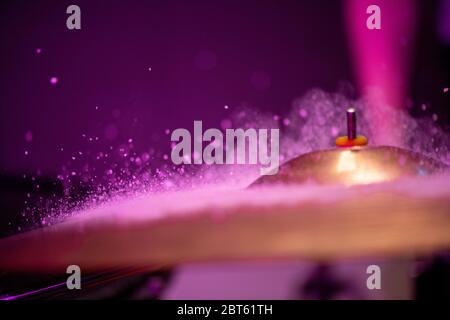 Raindrops or waterdrops hitting cymbal of golden color against purple background with copyspace on the left for your advert or notes Stock Photo