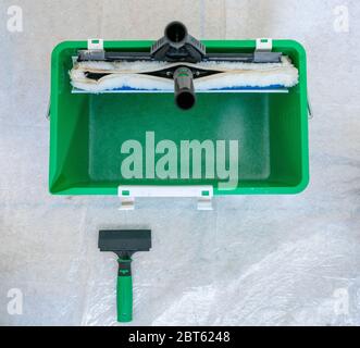 A top down view of  green bucket with window cleaning equipment and cleaning solution on a white protective floor mat Stock Photo