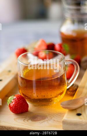 hot black tea with strawberry berries, on a wooden Board Stock Photo