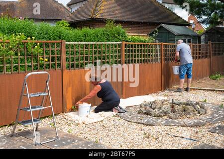 Ashford, Kent, UK. 23rd May, 2020. Friends and neighbours in the village of Hamstreet near Ashford in Kent occupy their time with chores about the house. This couple are busy at work painting the garden fence. ©Paul Lawrenson 2020, Photo Credit: Paul Lawrenson/Alamy Live News Stock Photo