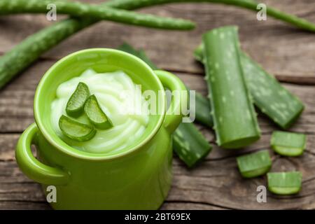 Aloe Vera Cream. Cream in a jar on a background of a wooden table and pieces of Aloe leaves Stock Photo