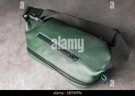Belt bag made of dark green textured leather, banana on a gray background. Handmade Stock Photo