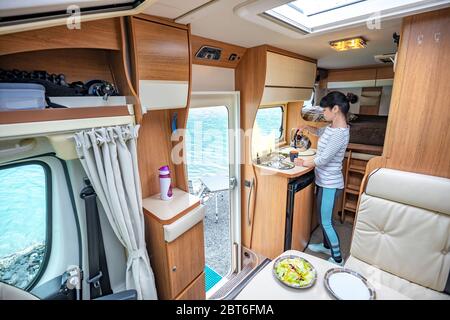 Woman cooking in camper, motorhome RV interior. Family vacation travel, holiday trip in motorhome, Caravan car Vacation. Stock Photo