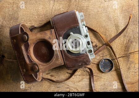 Ancient old vintage film camera with old lether cover on brown old wood background. Antique, vintage, grunge, classic concept