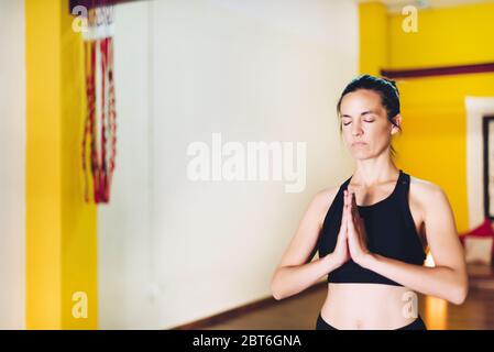 Woman doing yoga standing with hands together and eyes closed relaxed. Concept of Yoga Stock Photo